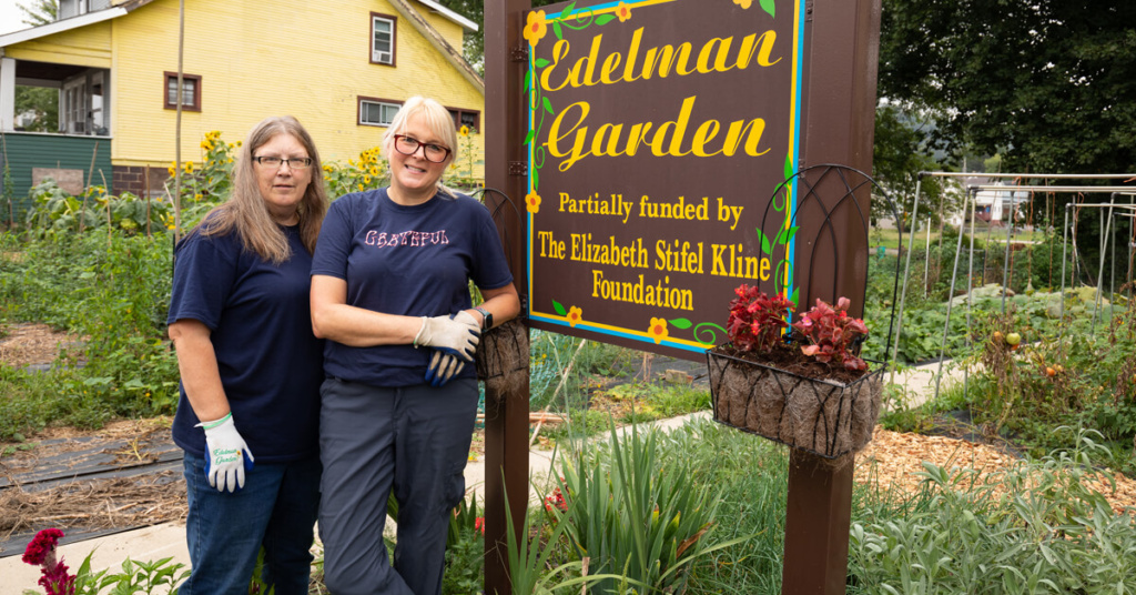 Meredith and Paula stand next to the Edelman Garden sign